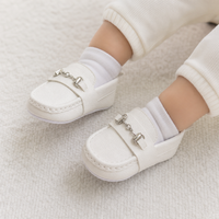 mocassins bébé blancs en cuir à chaînette portés aux pieds